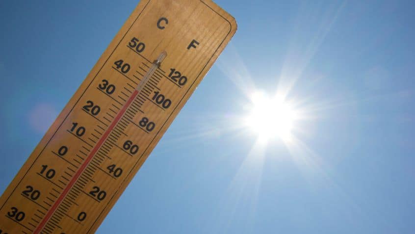 a thermometer held up at an angle to the sky. the sun is shining brightly next to it. the thermometer is up to 100 degrees fahrenheit.