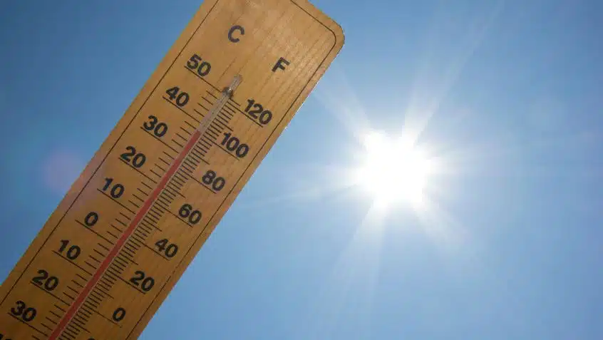 a thermometer held up at an angle to the sky. the sun is shining brightly next to it. the thermometer is up to 100 degrees fahrenheit.